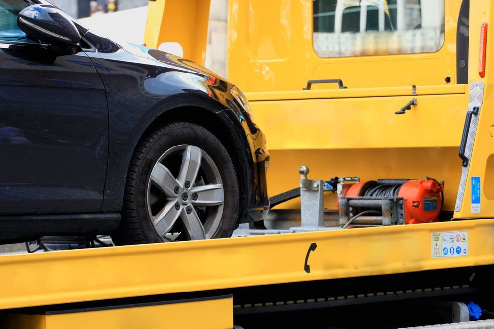 A Black Car is Sitting on Top of a Yellow Tow Truck — Mareeba Express Towing in Mareeba, QLD