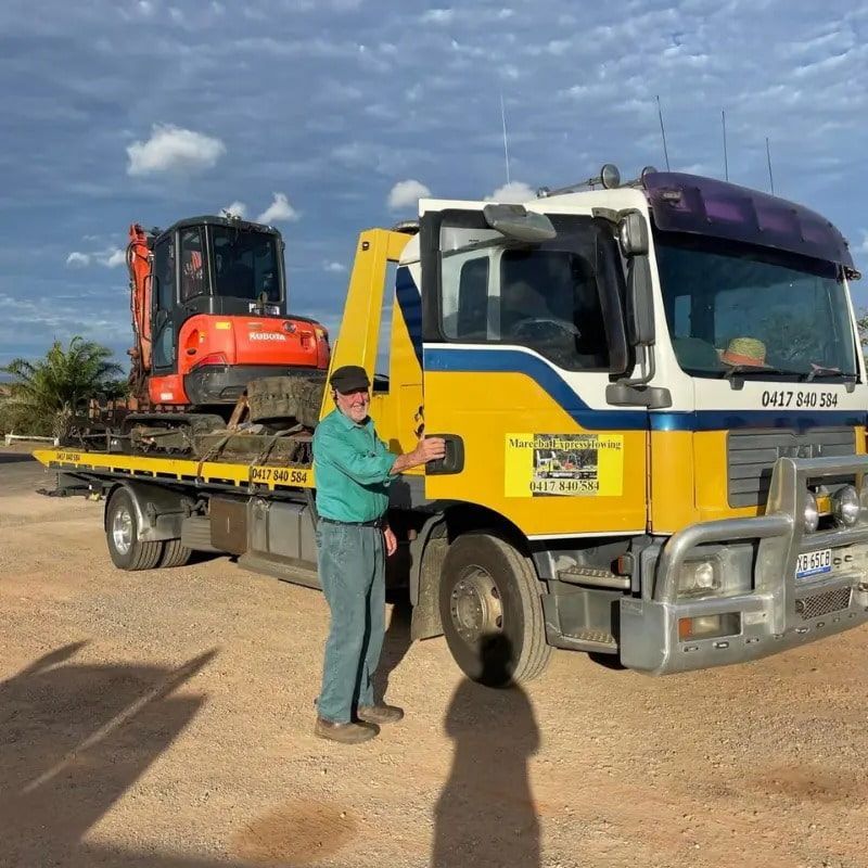 A Man is Standing Next to a Yellow Tow Truck — Mareeba Express Towing in Mareeba, QLD