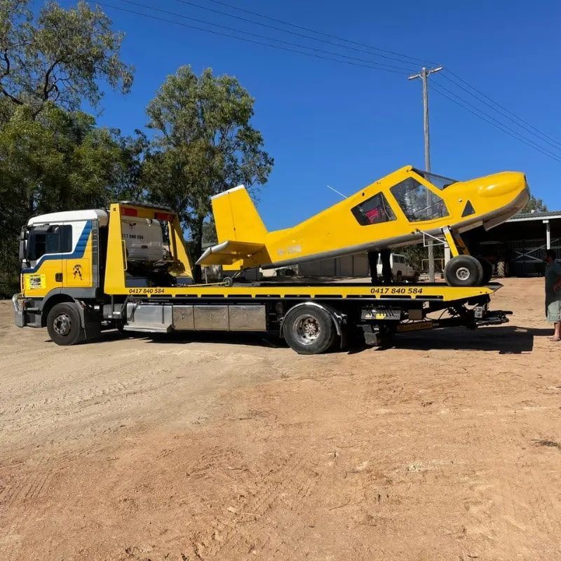 A Yellow Tow Truck is Carrying a Small Yellow Plane — Mareeba Express Towing in Atherton, QLD