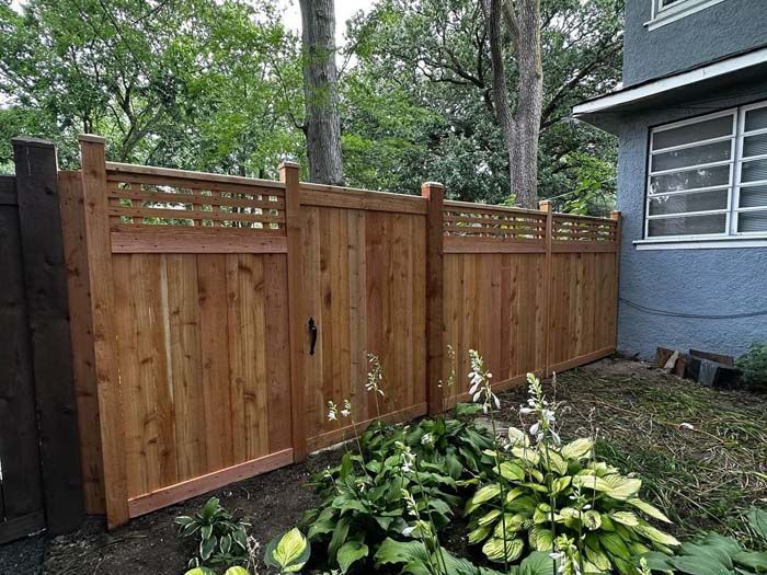A wooden fence with a gate in the backyard of a house.