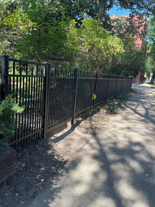 A black metal fence is along the side of a road.
