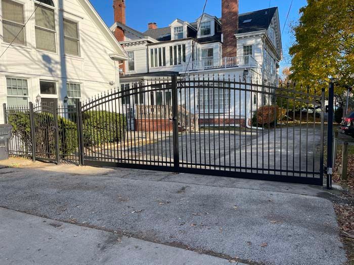 A black gate is sitting in front of a white house.