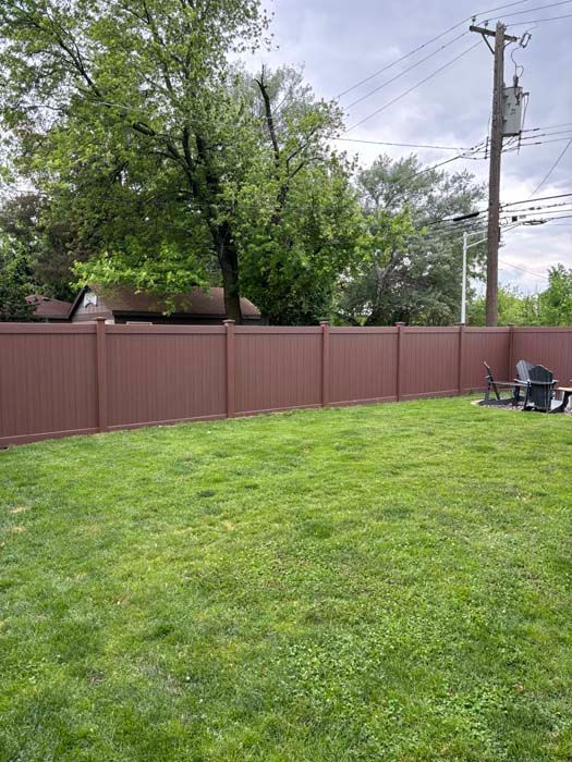 A backyard with a wooden fence and a lush green lawn.