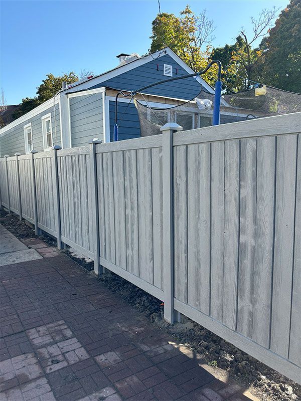 A patio with a table and chairs and a fence in the backyard.