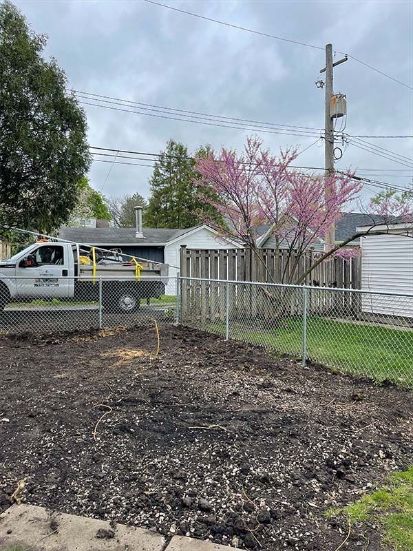 A chain link fence is surrounding a driveway next to a house.