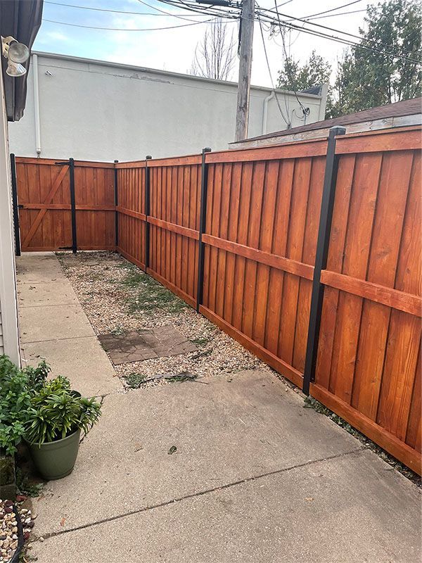 A wooden fence with a gate between two houses.