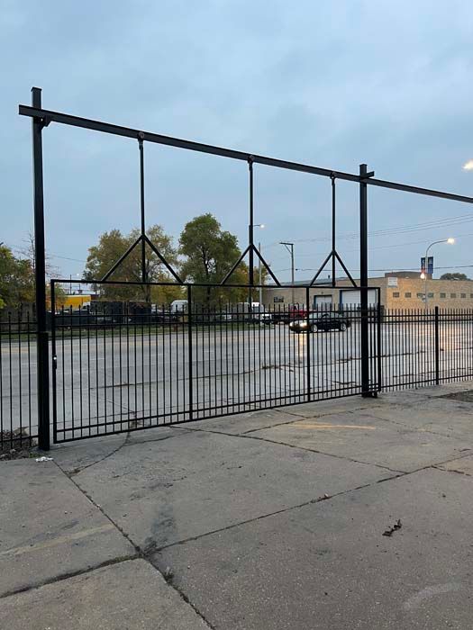 A black metal fence surrounds an empty parking lot.
