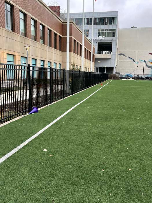 A soccer field with a fence and a building in the background.
