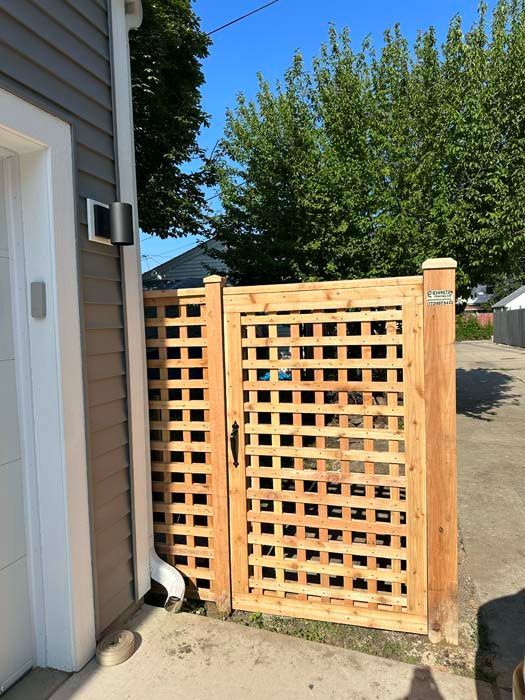 A wooden gate is sitting next to a garage door.