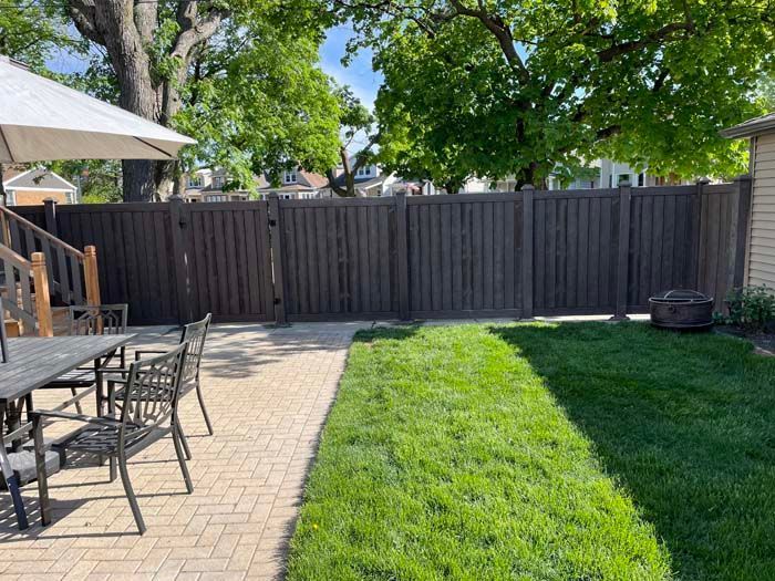 A patio with a table and chairs and a fence in the backyard.