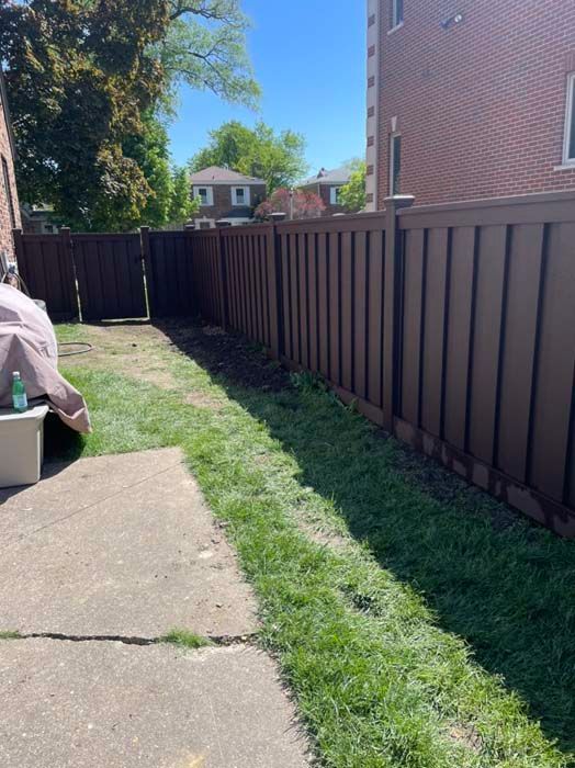 A backyard with a wooden fence and a concrete walkway