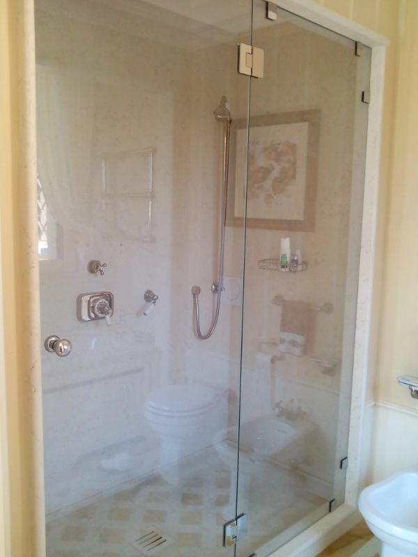 Box doccia in vetro in un bagno, dotato di WC, sanitari e opere d'arte incorniciate.