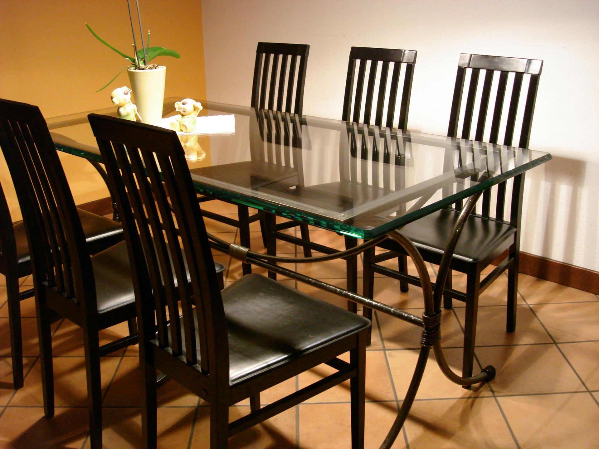 Tavolo da pranzo con piano in vetro e sedie nere.