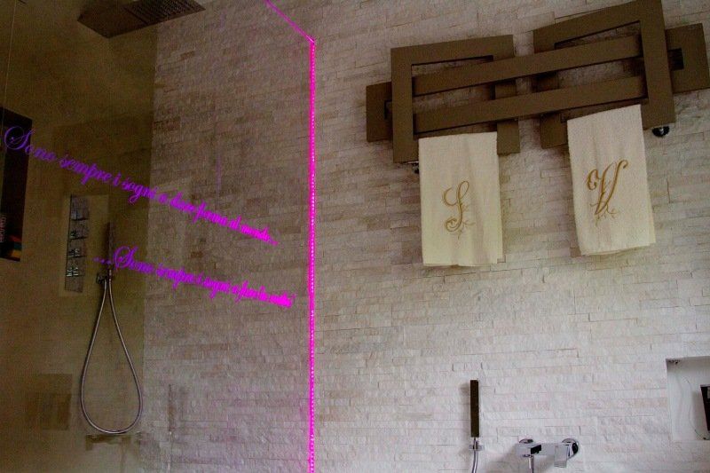 Doccia con pareti piastrellate beige e un portasciugamani con due asciugamani con le lettere 