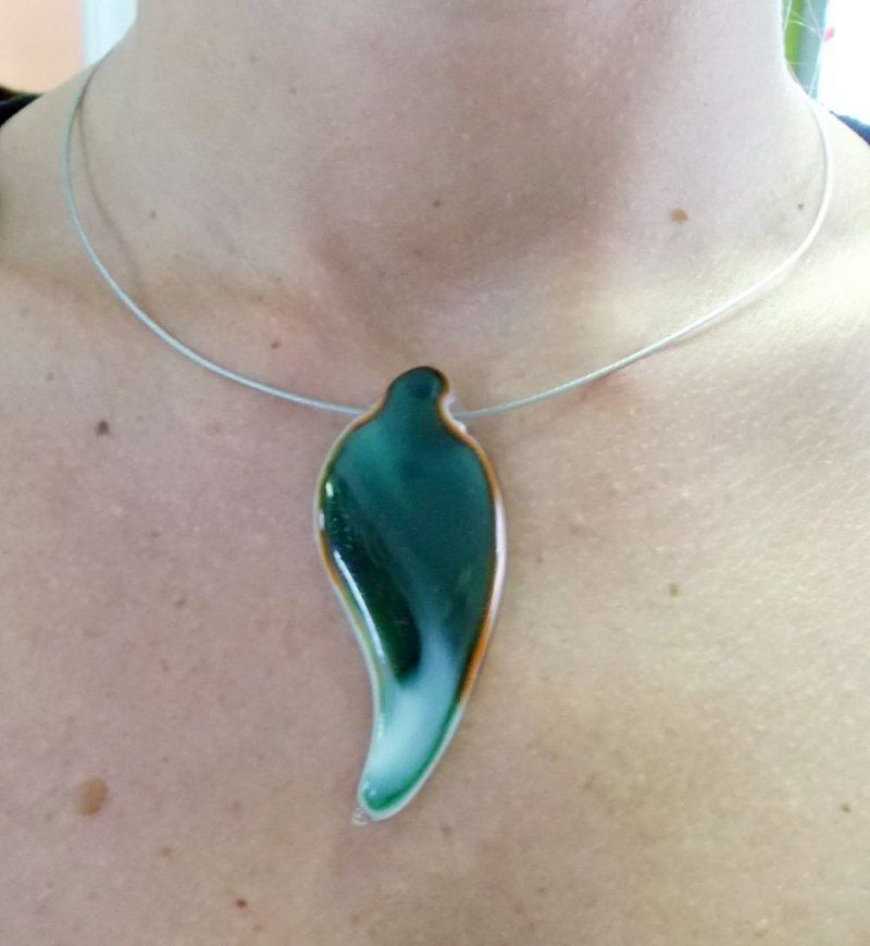 Collana con pendente a forma di foglia verde e bianca su un girocollo in filo d'argento da indossare intorno al collo.