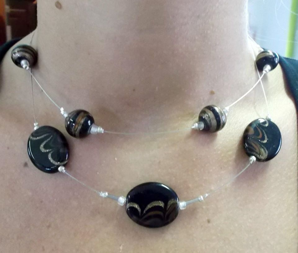 Collana di perline nere e dorate al collo di una persona.