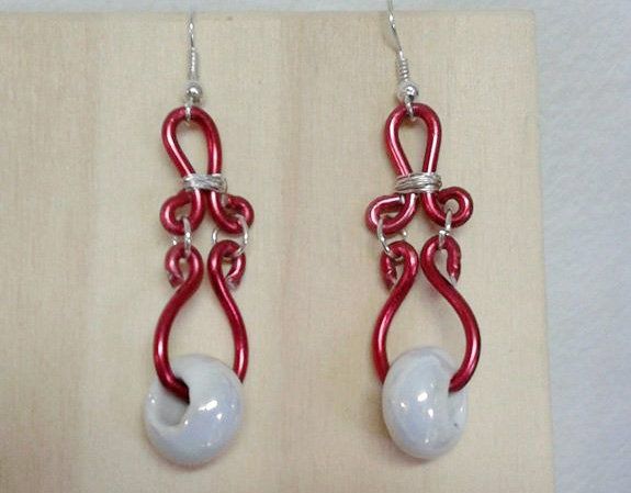 Orecchini in filo rosso e argento con perline bianche a forma di lacrima.