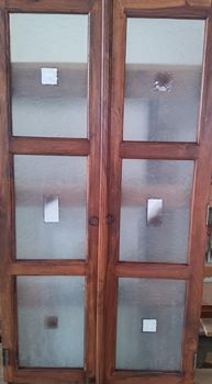 Porte doppie in legno con pannelli in vetro smerigliato e motivo quadrato.