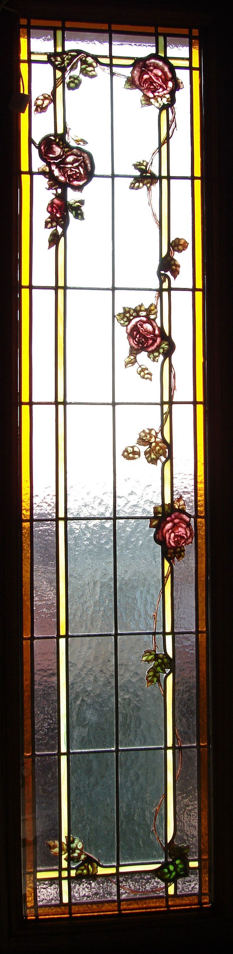 Vetrata raffigurante rose rosa e foglie verdi su uno sfondo di vetro testurizzato con bordo giallo.