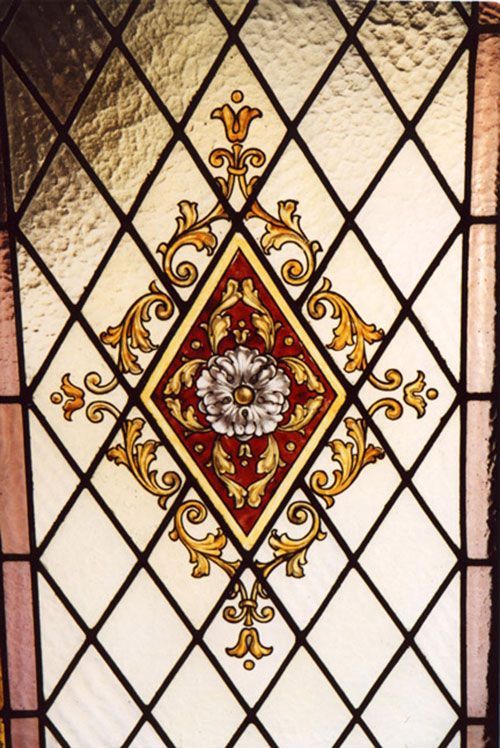Vetrata con griglia a rombi e motivo floreale decorato in rosso e oro.