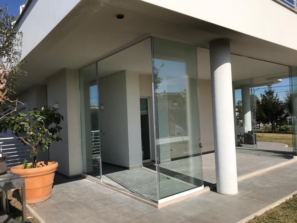 Ingresso di un edificio moderno con pareti in vetro, una pianta in vaso e un patio in cemento.