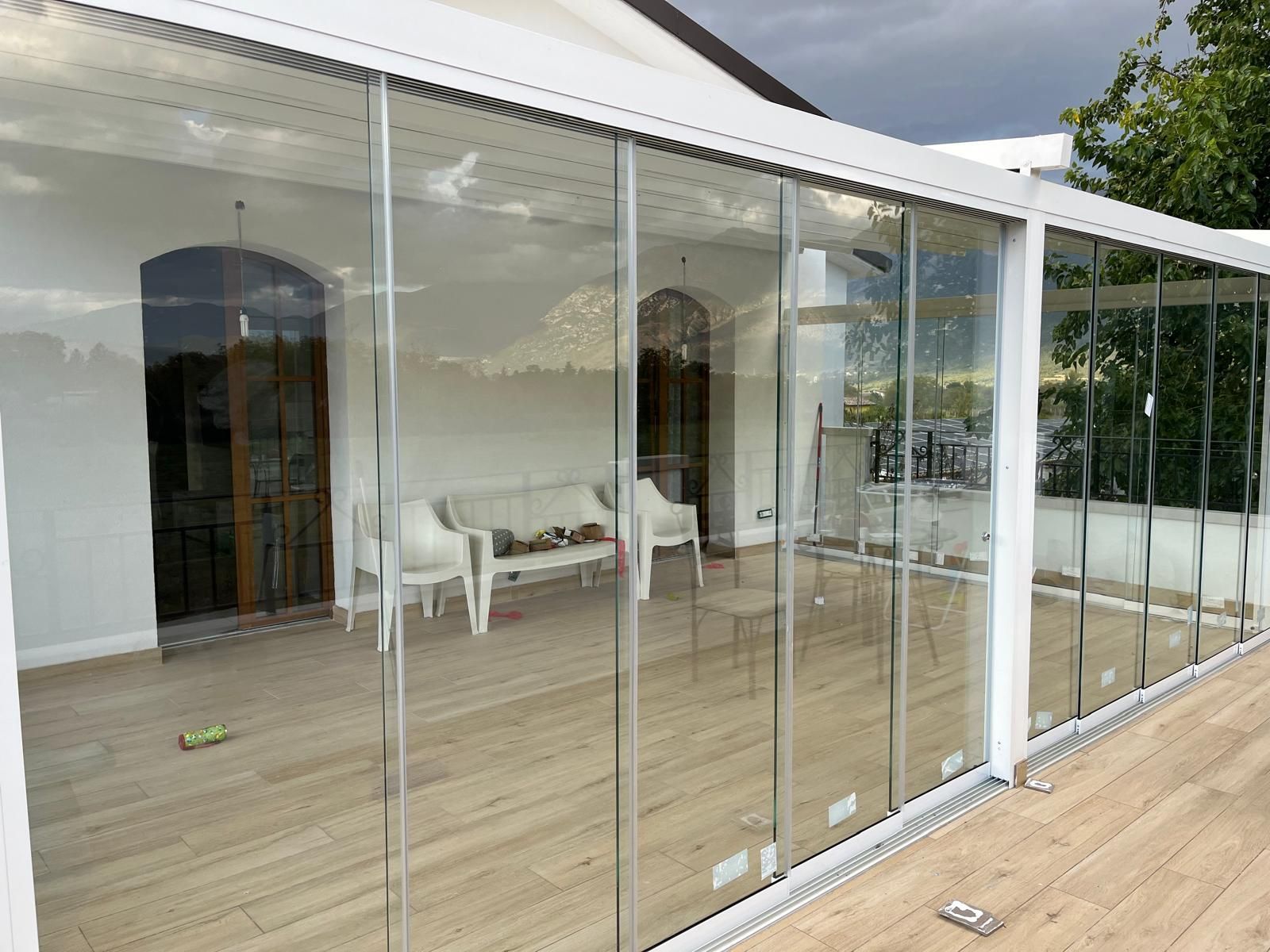 Patio con vetrate e mobili bianchi. Tetto bianco. Pavimento in legno.
