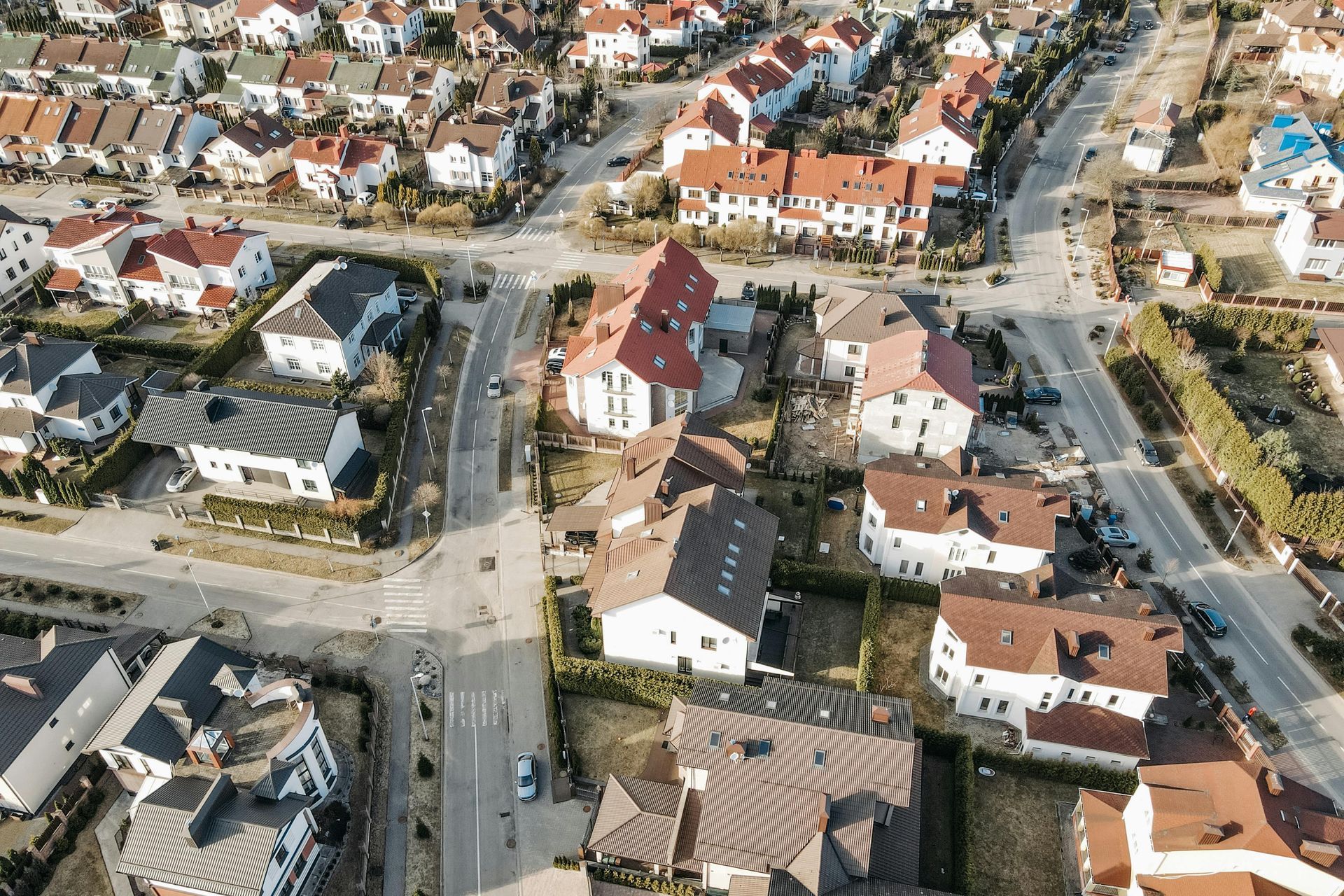 Aerial view of a suburban neighborhood with houses, streets, and parked cars.