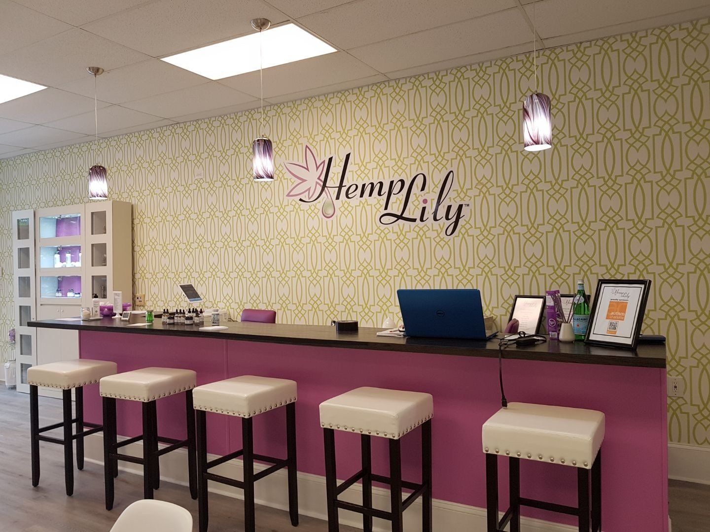 Inside a shop, a pink bar with white stools; 