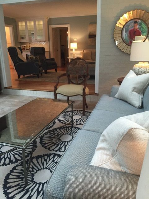 Living room with a patterned rug, blue sofa, and view into adjacent rooms.