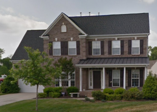 A large brick house with a white truck parked in front of it
