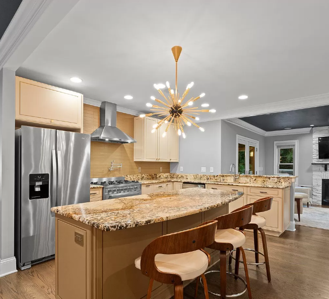 Modern kitchen with island, stainless steel appliances, and a gold sputnik chandelier.