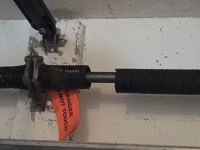 Garage door torsion spring with warning tag.