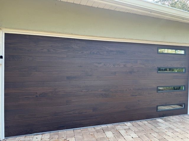 Dark brown horizontal plank garage door with three rectangular windows.