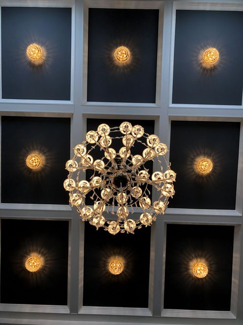 Modern chandelier with glowing bulbs in a grid-like ceiling alcove