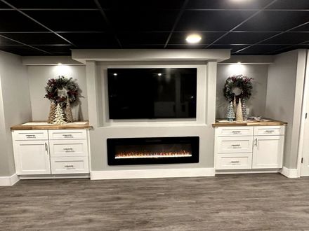 Modern living room with a wall-mounted TV, electric fireplace, and two decorated white cabinets