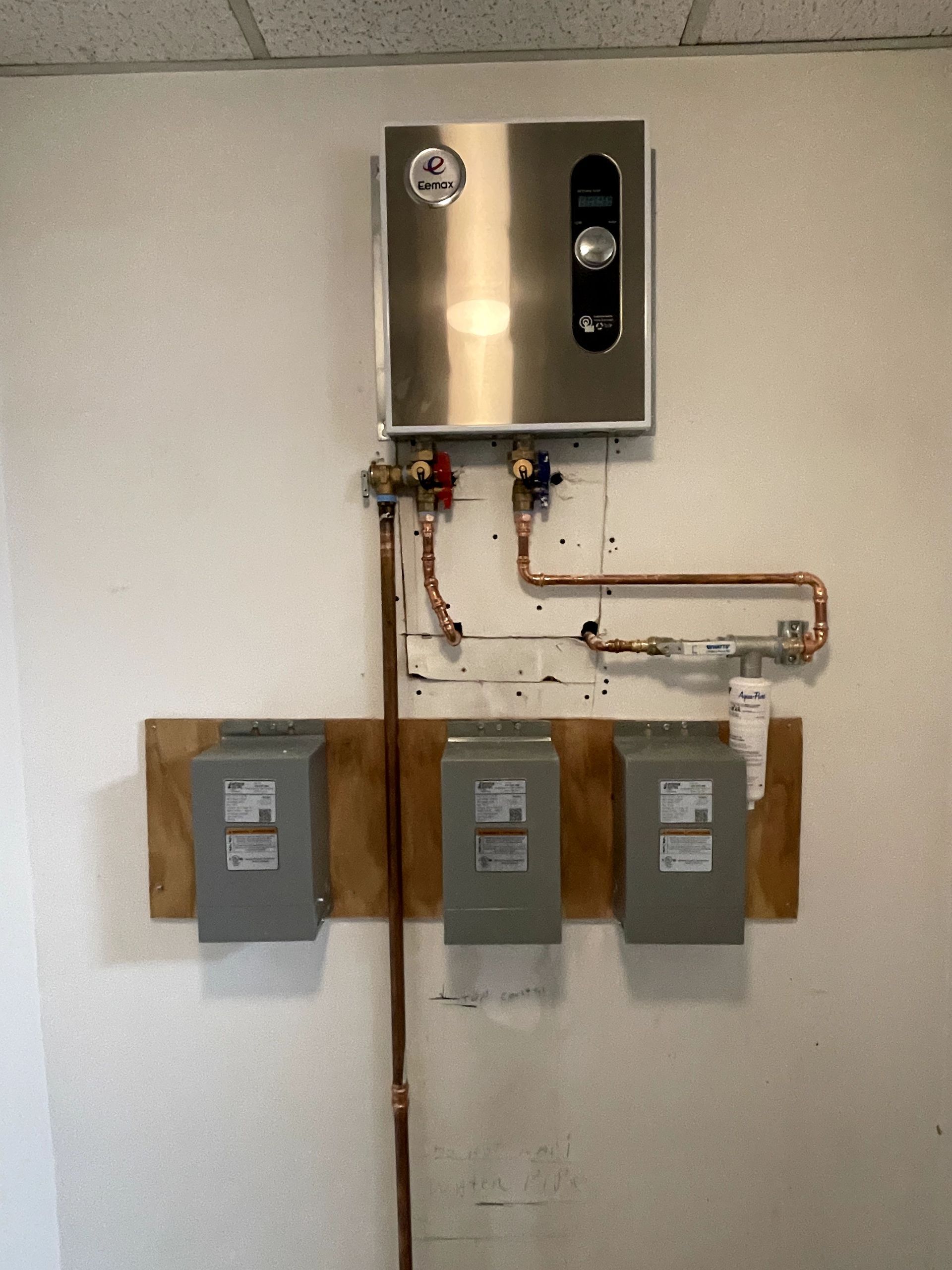 Wall-mounted electrical boxes, meter panel, and copper piping on a white wall