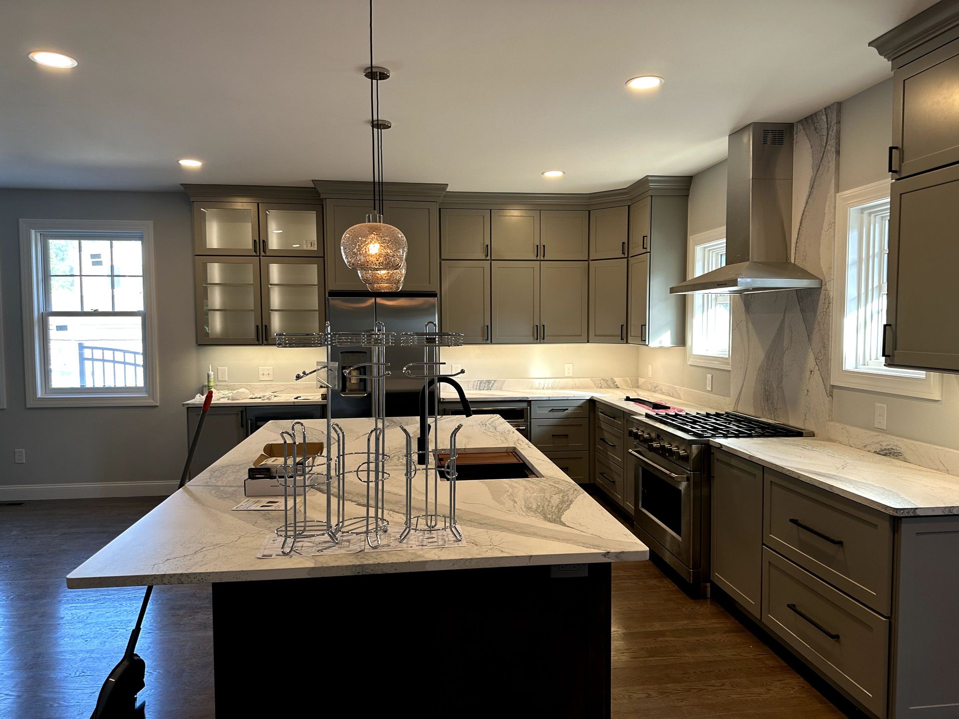 Modern kitchen with a large island, gray cabinets, stainless appliances, and pendant lighting.