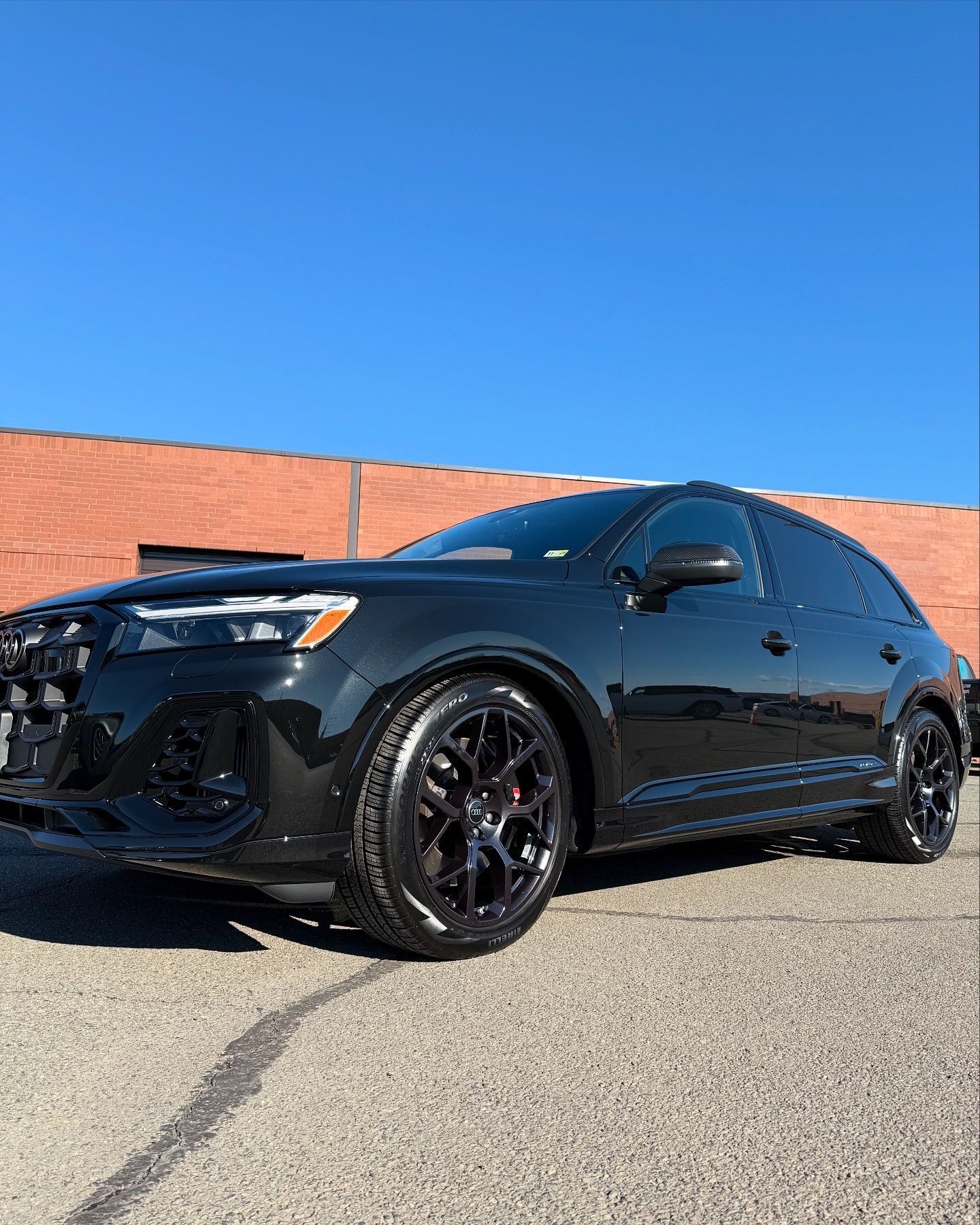 Black sports hatchback parked outdoors against a brick wall under a clear blue sky