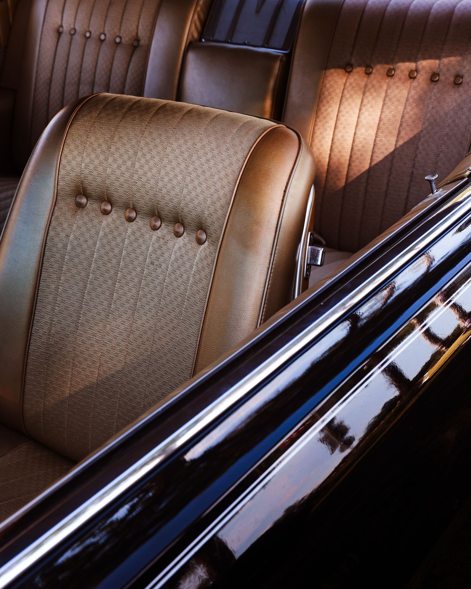 Vintage car interior with tan leather seats and polished wood paneling in warm sunlight