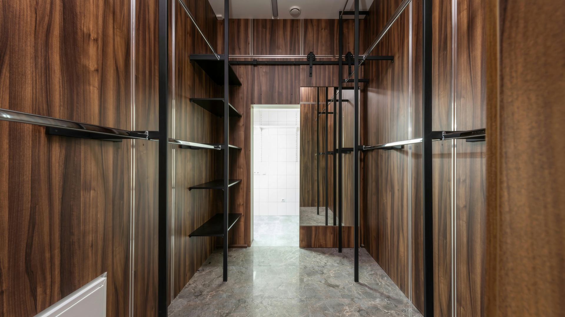 A retail store interior with wooden walls, black metal display racks, and a doorway.
