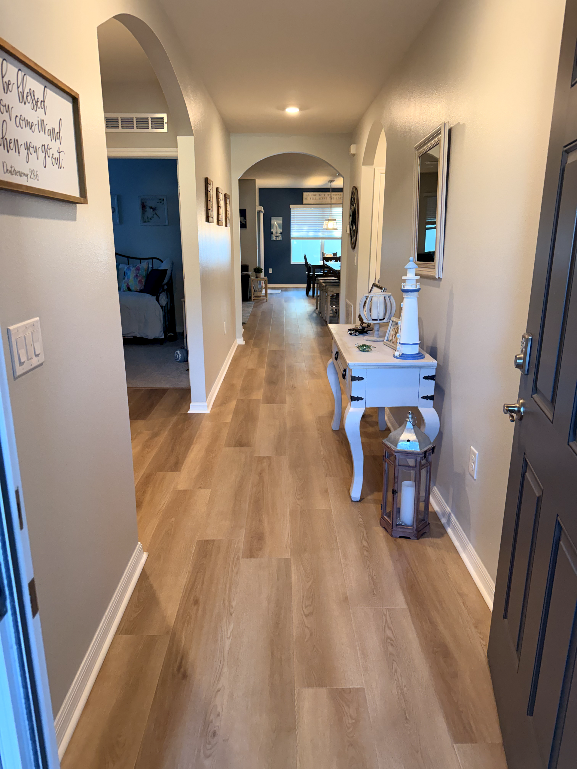 Hallway with light wood floors, gray walls, and a decorative white table.