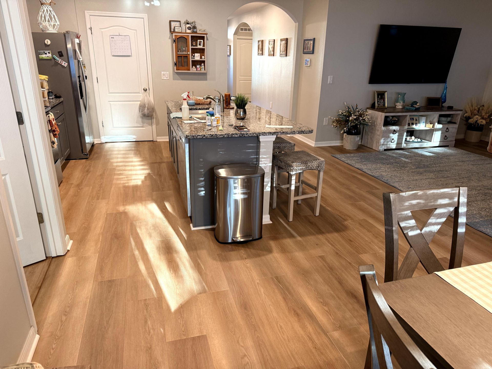 Hardwood floor kitchen and dining area with island, cabinets, and stainless steel trash can.