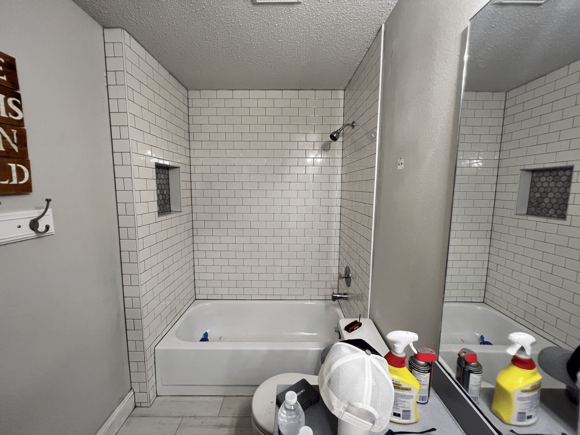 Bathroom with white subway tile walls, bathtub, and a mirror.