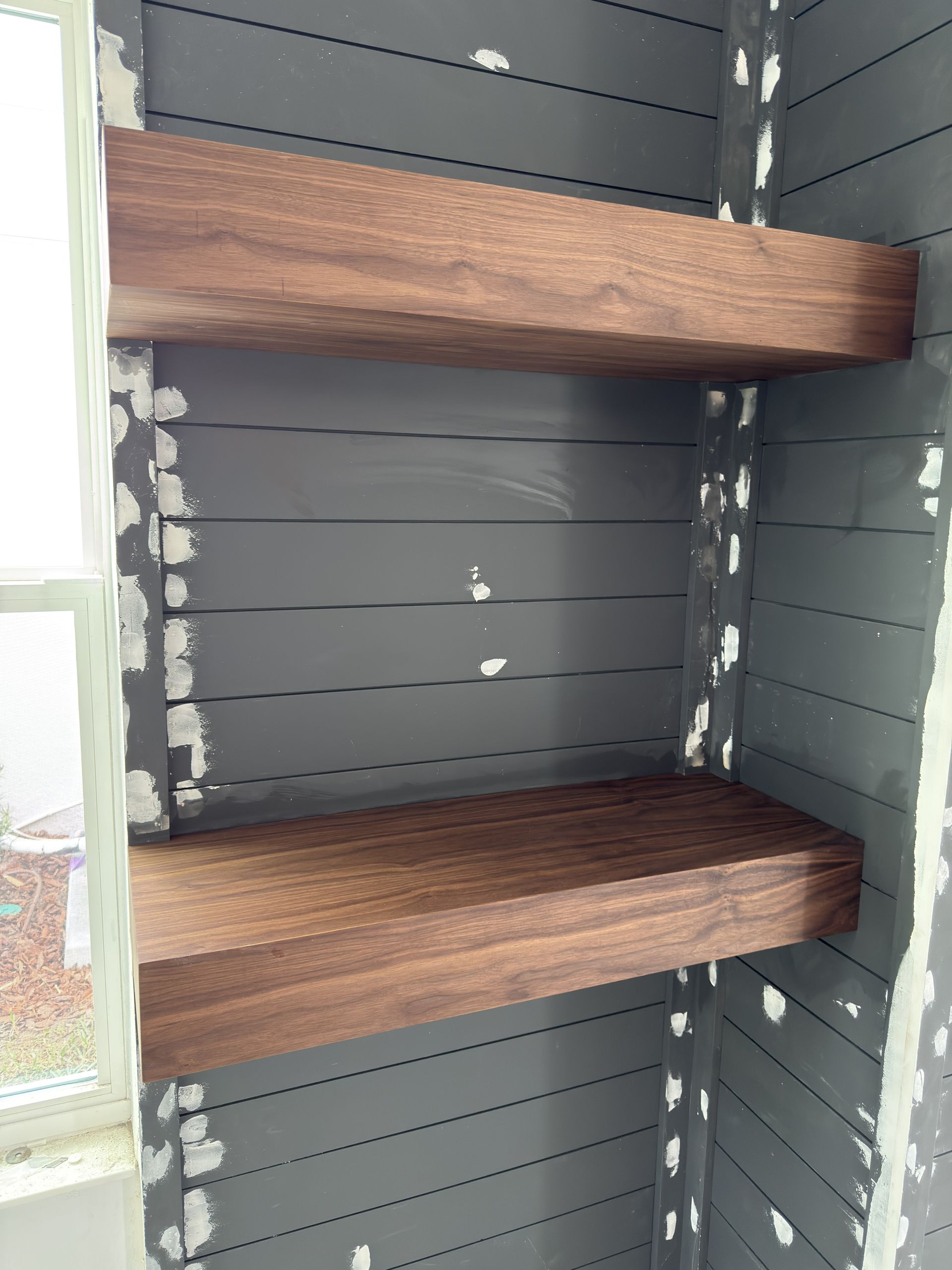 Two stained wooden shelves built into a gray-painted alcove.