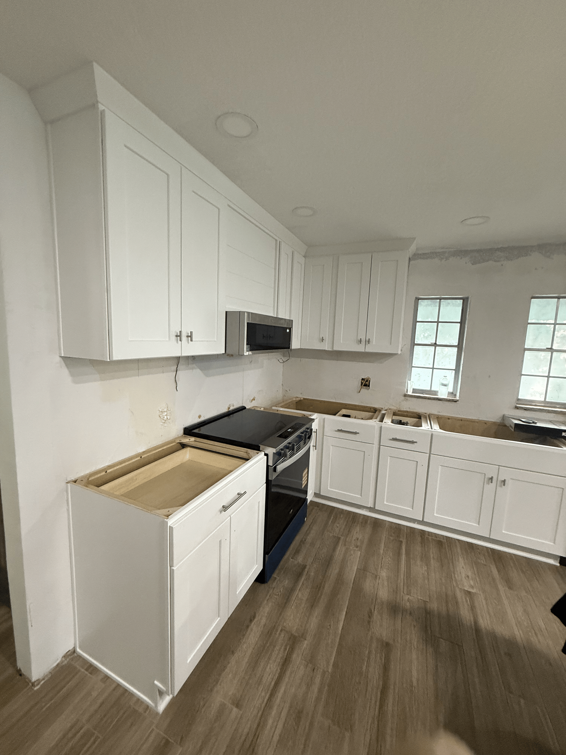 White kitchen cabinets and oven installed in a room with wood-look flooring.