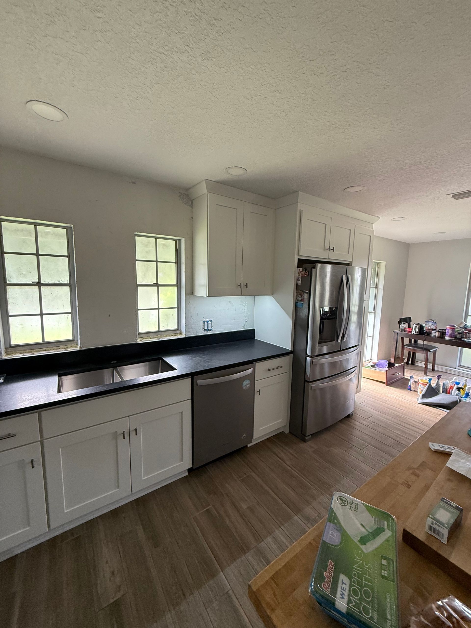White kitchen with black countertops, stainless steel appliances, and wood-look flooring.
