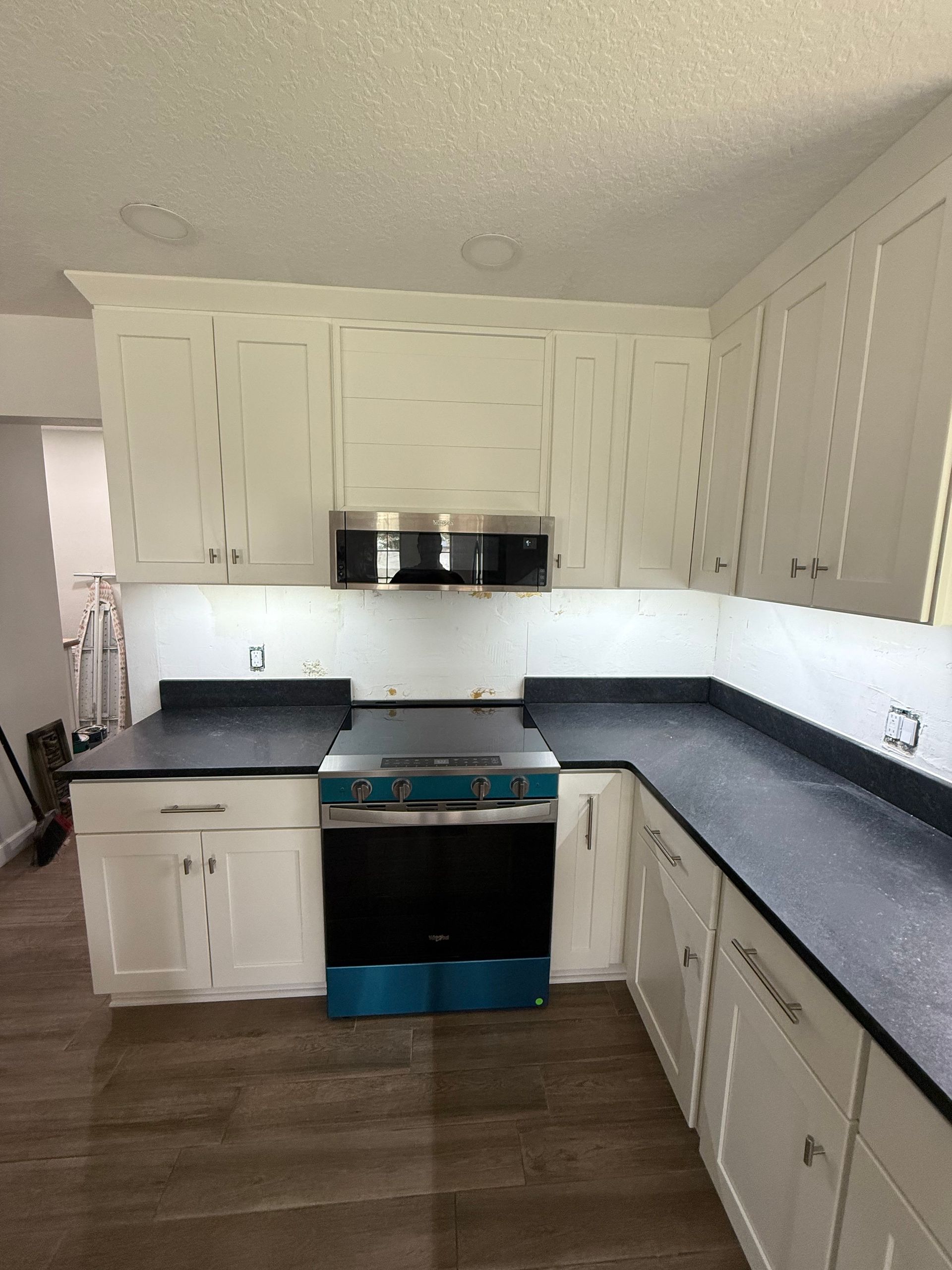 White kitchen cabinets with black countertops and a stainless steel oven.