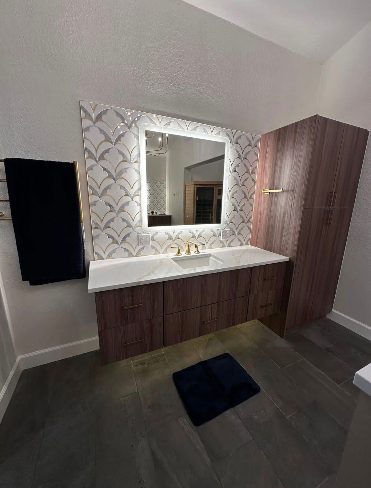 Modern bathroom with a wood vanity, white countertop, and patterned backsplash.