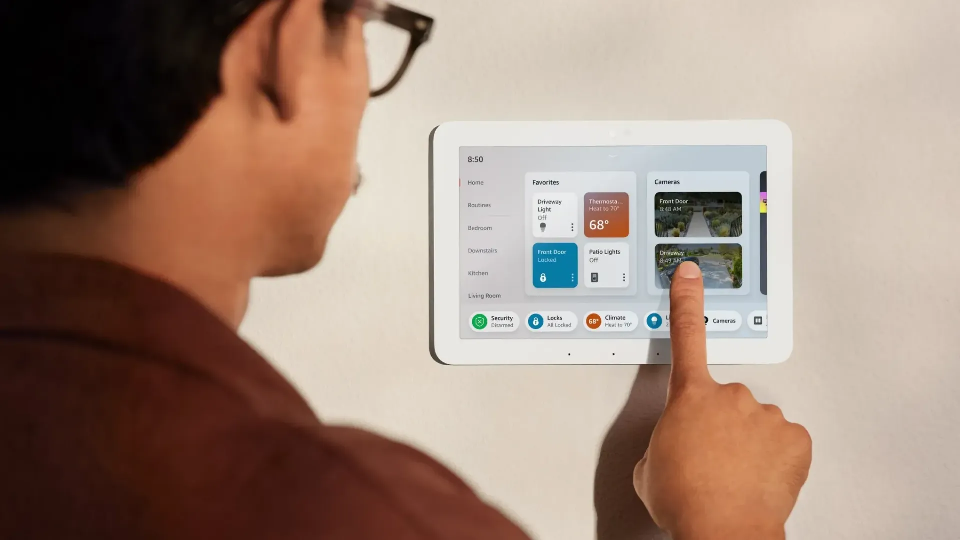Person interacting with a wall-mounted tablet displaying smart home controls, pointing at a screen.