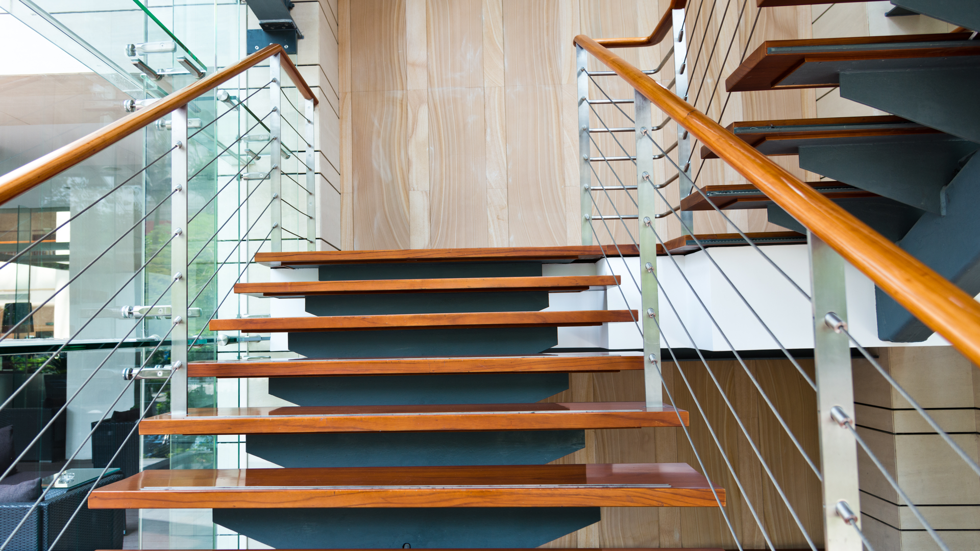 Wooden staircase with steel cable railings and wood handrail.